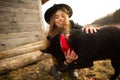 Happy young woman plaing with her black dog Brovko Vivchar in fron of old wooden house