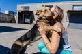 Happy young woman playing with her dog in the street Royalty Free Stock Photo