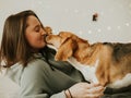 Happy young woman playing with her dog on a white background. Beagle dog with owner. Girl and dog at home