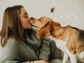 Happy young woman playing with her dog on a white background. Beagle dog with owner. Girl and dog at home