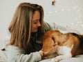 Happy young woman playing with her dog on a white background. Beagle dog with owner. Girl and dog at home