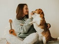 Happy young woman playing with her dog on a white background. Beagle dog with owner. Girl and dog at home