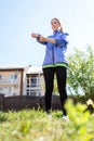 A happy young woman is playing sports in the yard, adjusting the sleeve of her windbreaker. View from below, from the grass.