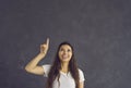 Happy young woman pointing index finger up at copy space recommending something. Royalty Free Stock Photo