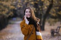 Happy young woman portrait in autumn park using phone Royalty Free Stock Photo