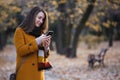 Happy young woman portrait in autumn park using phone Royalty Free Stock Photo