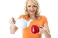 Happy Young Woman Pouring Tea from a Teapot Royalty Free Stock Photo