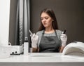 Happy young woman profession manicurist with scissors and nail polish on gray background