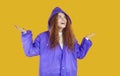 Happy young woman in purple raincoat looking up, spreading her hands and smiling Royalty Free Stock Photo