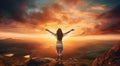 Happy young woman with raised hands standing on top of the mountain and looking at sunset Royalty Free Stock Photo