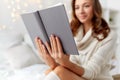 Happy young woman reading book in bed at home Royalty Free Stock Photo