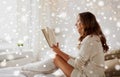 Happy young woman reading book in bed at home Royalty Free Stock Photo