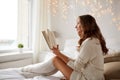 Happy young woman reading book in bed at home Royalty Free Stock Photo