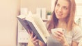 Happy young woman reading a book and drinking coffee on her couch Royalty Free Stock Photo