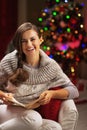 Happy young woman reading book near christmas tree Royalty Free Stock Photo