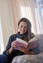 Happy, young woman and reading book on sofa for story, novel or learning knowledge at home. Relax, female person and Royalty Free Stock Photo