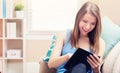 Happy young woman reading an e-book on her couch Royalty Free Stock Photo