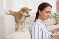 Happy young woman reading magazine with cute dog in living room Royalty Free Stock Photo