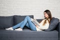 Happy young woman reading storybook on couch at home Royalty Free Stock Photo