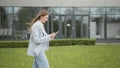 Happy young woman receiving discount for shopping while checking email box while walking in urban setting down street Royalty Free Stock Photo