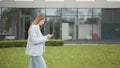 Happy young woman receiving discount for shopping while checking email box while walking in urban setting down street Royalty Free Stock Photo