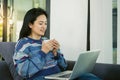 Happy young woman is relaxing on comfortable couch and using laptop at home. Royalty Free Stock Photo