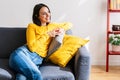 Happy young woman relaxing on couch while drinking tomato juice at home