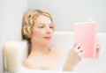 Happy young woman relaxing and reading a book in the bath Royalty Free Stock Photo