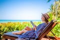 Happy young woman relaxing on wooden deck chair at luxury villa Royalty Free Stock Photo