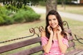 Happy young woman resting on bench in park Royalty Free Stock Photo