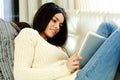 Happy young woman resting on a sofa with tablet computer Royalty Free Stock Photo