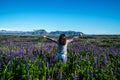 Happy young woman runs in lupin field in Iceland