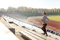 Happy young woman running upstairs on stadium