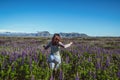 Happy young woman runs in lupin field in Iceland