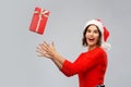 Happy young woman in santa hat catching gift box Royalty Free Stock Photo