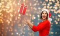 Happy young woman in santa hat catching gift box Royalty Free Stock Photo