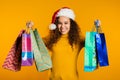 Happy young woman in Santa hat with colorful paper bags after shopping isolated Royalty Free Stock Photo