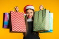 Happy young woman in Santa hat with colorful paper bags after shopping isolated Royalty Free Stock Photo