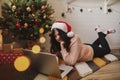 Happy young woman in santa hat having video call with family on laptop under christmas tree Royalty Free Stock Photo