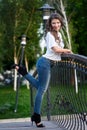 Happy young woman in shirt and jeans standing on the bridge