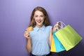 Happy young woman with shopping bags and credit card on color background Royalty Free Stock Photo