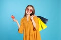 Happy young woman with shopping bags and credit card on light blue background. Big sale Royalty Free Stock Photo
