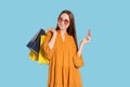 Happy young woman with shopping bags and credit card on light blue background. Big sale Royalty Free Stock Photo