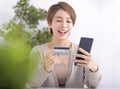 Happy young woman shopping online with mobile phone and credit card Royalty Free Stock Photo