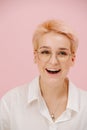 Happy young woman with short blond hair, round glasses and stars eye makeup