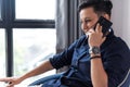 Happy young woman in short hair cut and dark blue shirt is smiling and talking on the mobile phone Royalty Free Stock Photo