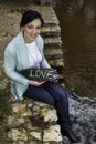 Happy young woman showing the words, Love, on a stone Royalty Free Stock Photo