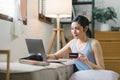 A happy young woman is shown shopping online using her laptop and credit card at home. Royalty Free Stock Photo