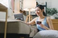 A happy young woman is shown shopping online using her laptop and credit card at home. Royalty Free Stock Photo