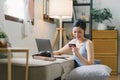 A happy young woman is shown shopping online using her laptop and credit card at home. Royalty Free Stock Photo